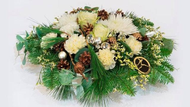 En vakker blomsteroppsats med hvite roser, granbar, kongler og dekorative elementer.