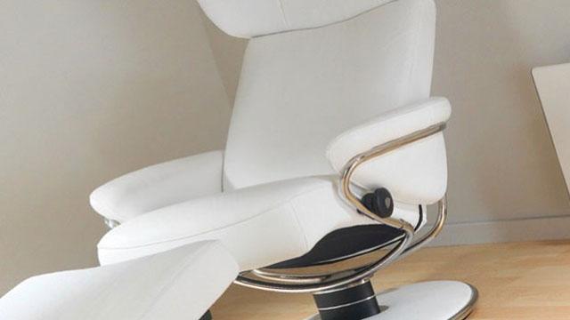 Hvit lenestol med moderne design og metallramme, plassert på et lyst tregulv.