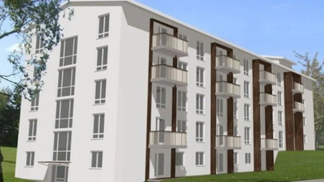 Moderne leilighetsbygg med balkonger og store vinduer, omgitt av grønt område.