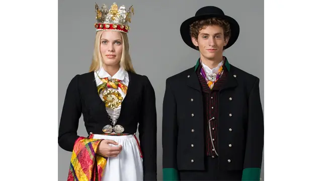Kvinne og mann i tradisjonelle norske bunader, med detaljerte broderier og tilbehør.