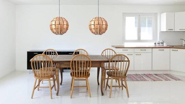 Moderne kjøkken med et trebord, fire stoler, og to kobberlamper hengende fra taket.