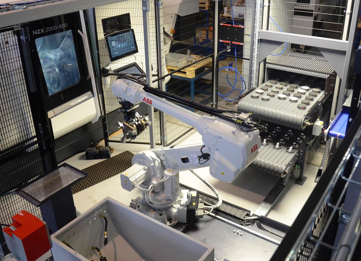 Industriell robotarm i en automatisert produksjonslinje med maskiner og kontrollpaneler.