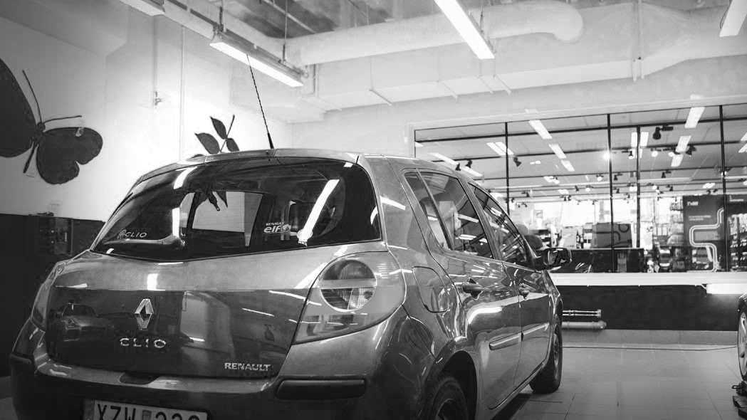 En sølvfarget Renault Clio parkert inne i en moderne bilvask med store vinduer.