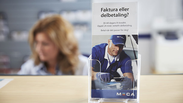 Informasjonsbrosjyre om faktura eller delbetaling i en butikk, med en ansatt i bakgrunnen.
