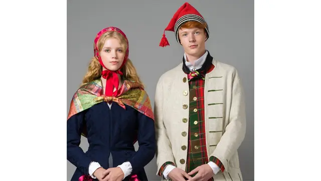 To personer i tradisjonelle norske bunader, en kvinne med sjal og en mann med lue og jakke.