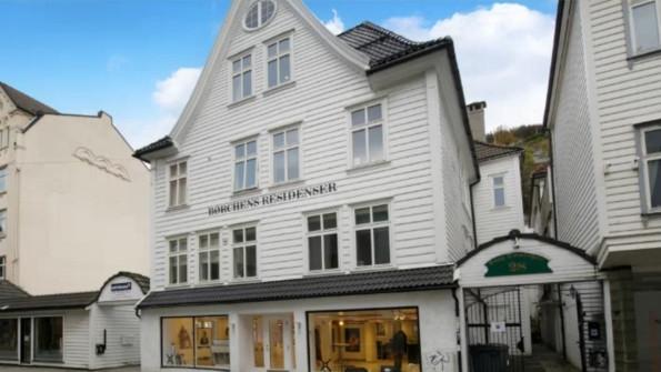 En hvit bygning med flere vinduer og en inngang, plassert i en gate i Bergen, Norge.