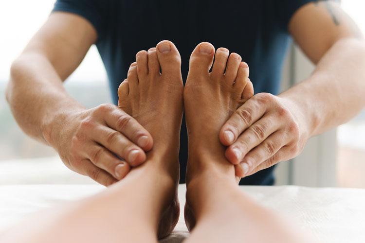 En person får fotmassasje av en terapeut med hender som masserer føttene.