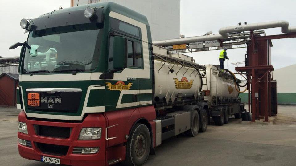 En lastebil med tank på vei til å laste av innholdet ved en industriell anlegg.