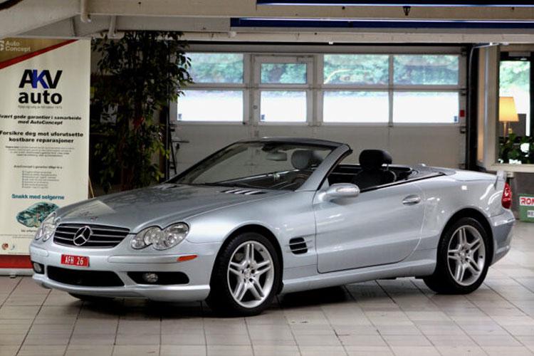 En sølvfarget Mercedes-Benz sportsbil med åpen tak, parkert i en bilutstillingshall.