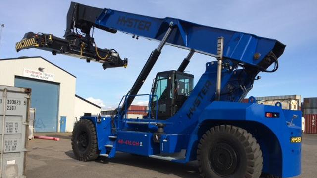 Blå Hyster gaffeltruck med lang arm som løfter en container på en havn.