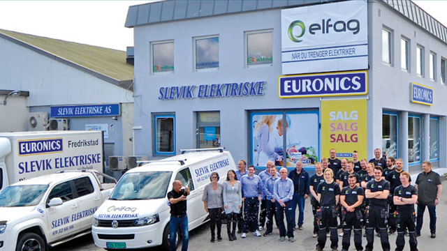 En gruppe ansatte foran Slevik Elektriske med to varebiler og bygningen i bakgrunnen. Euronics-skilt synlig.