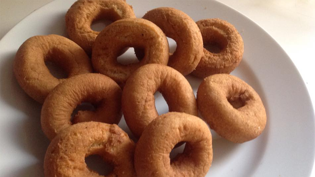 En tallerken med flere brune donuts med hull i midten, perfekt for en søt snack.