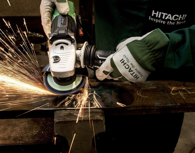 En person bruker en vinkelsliper med gnister som spruter, mens de arbeider med metall.