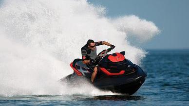 En person kjører en vannscooter på havet, med sprut av vann som spruter bak.