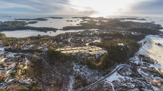Luftbilde av et kystlandskap med øyer, skog og snødekte områder under en lys himmel.