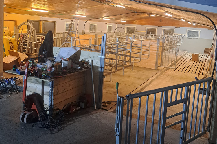 En innendørs stall med metalldeler, verktøy og en uferdig oppbevaringsplass. Lys belysning i taket.