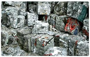 Kompakte sølvfargede metallblokker stablet i en haug på en resirkuleringsplass.