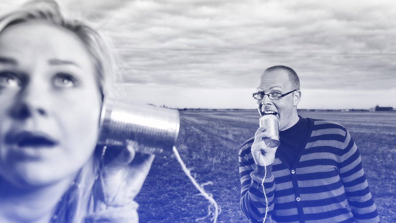 To personer i en åpen mark, en kvinne lytter til en boks, mens en mann snakker i en annen boks.