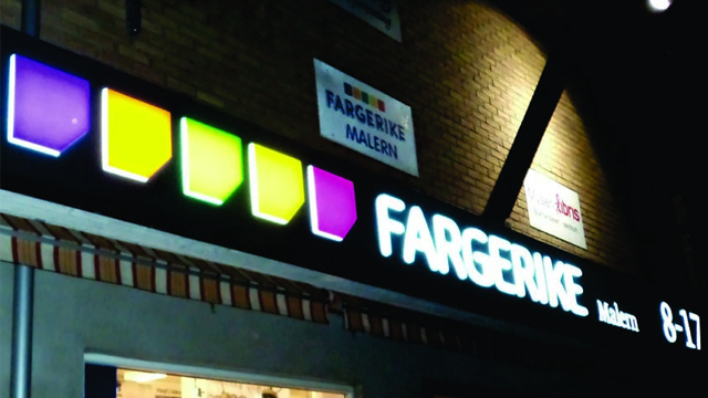 Fargerike butikk med fargerike skilt og logo, beliggende på en murvegg.