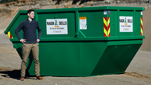 En mann står ved siden av en stor grønn container med teksten "Ragn-Sells" på.