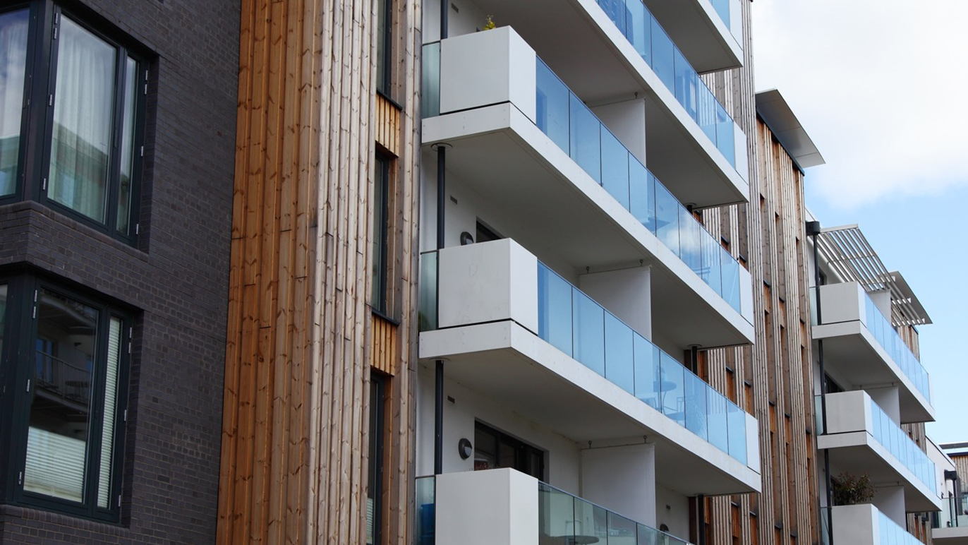 Moderne leilighetsbygg med balkonger og trepanel på fasaden.