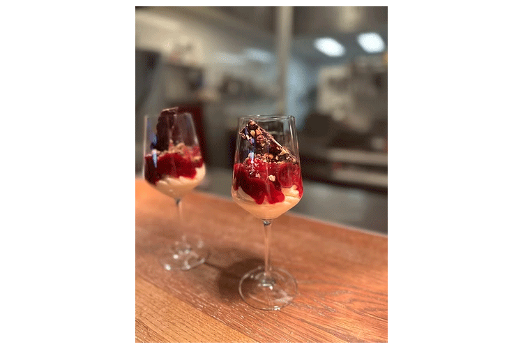 To glass med dessert laget av krem, bær og sjokolade, servert på en treoverflate.