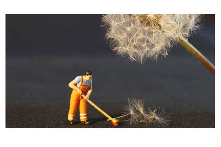 En liten figur i arbeidsklær som feier dandelionfrø med en kost.