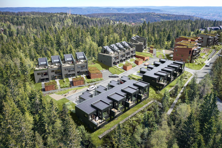 Moderne boliger i skogkledd område med flere bygninger og parkeringsplasser. Utsikt over landskapet i bakgrunnen.