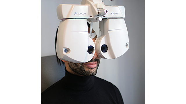 En person som bruker en synstestmaskin for øyeundersøkelse i et optikerkontor.