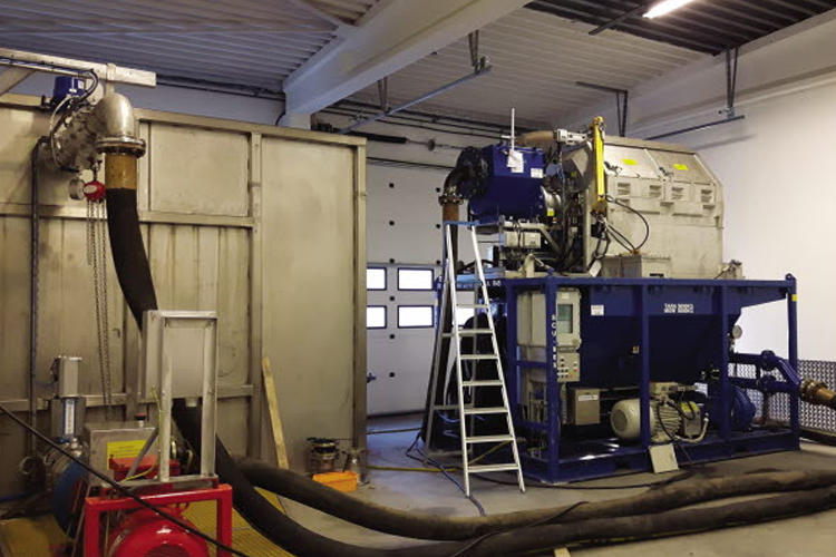 Industrielt utstyr i et verksted, inkludert en stor maskin og tilkoblede slanger.