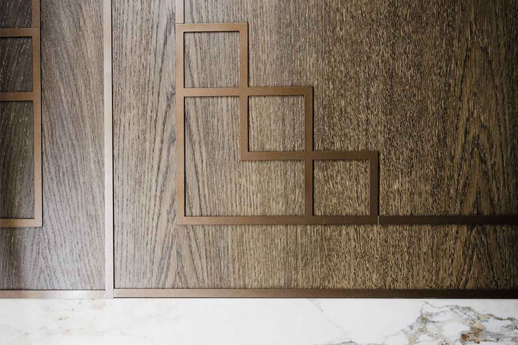 Mønster av brune treplater med geometriske former i metallisk finish på en marmoroverflate.