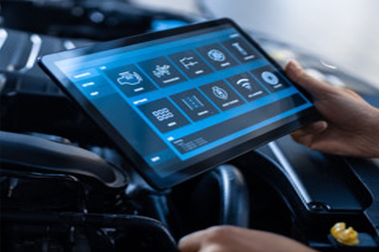 En person som holder et nettbrett over motoren i en bil, med digitale kontroller og informasjonsskjerm.