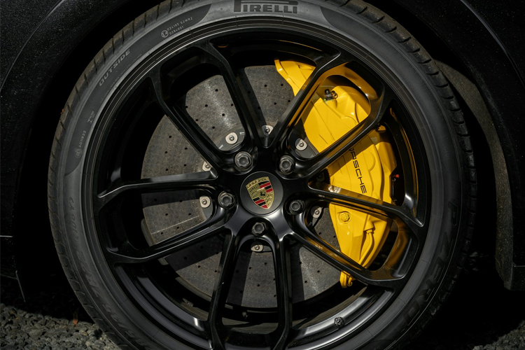 Nærbilde av en svart felg med gule bremsekalipere på en Porsche, med detaljerte bremseplater.