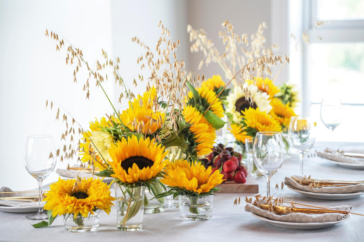 Et vakkert dekket bord med solblomster, druer og glass, perfekt for en festlig anledning.