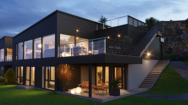 Moderne hus med stor terrasse, belyst om kvelden, omgitt av grønt gress og steintrapp.