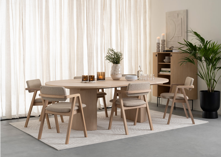Moderne spisestue med rundt bord, stoler i tre, planter og dekorative elementer i et lyst rom.