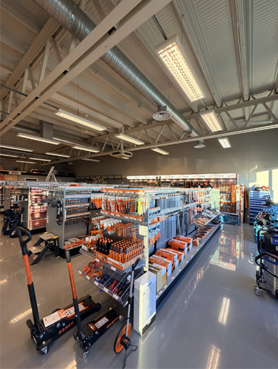 Butikkinnredning med verktøy og utstyr på hyller, godt opplyst rom med moderne design.