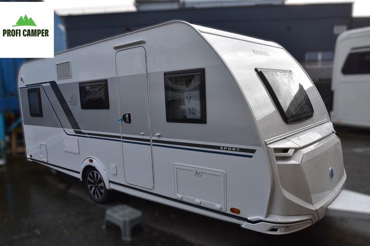 En moderne campingvogn med en strømlinjeformet design, parkert på en grå overflate.