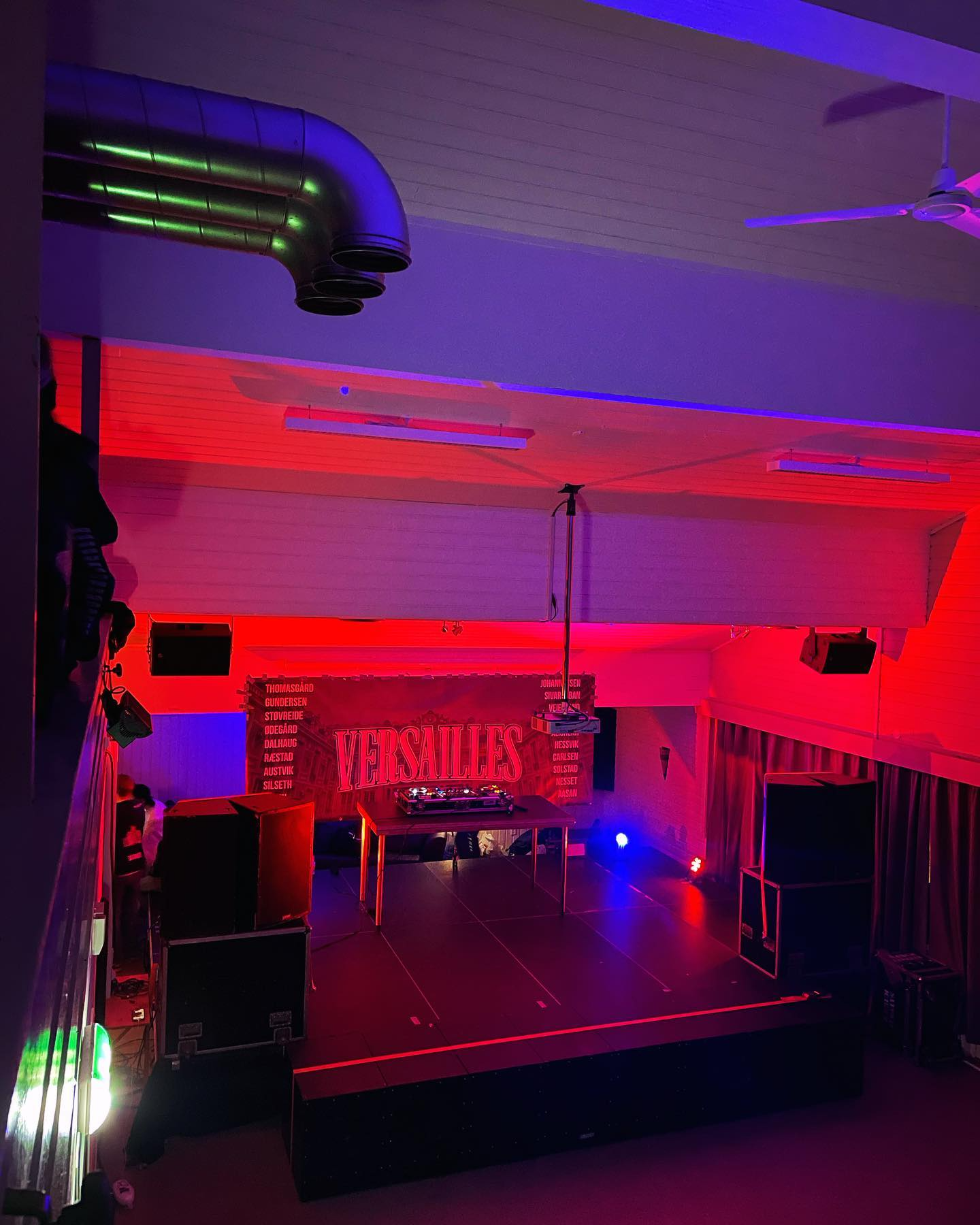 En scene med DJ-utstyr i et rom med rød og blå belysning, klar for fest eller konsert.