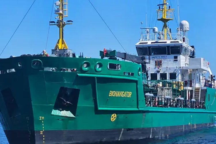 Grønn tankskip med navnet "Bonnigton" ligger til kai under klar blå himmel.