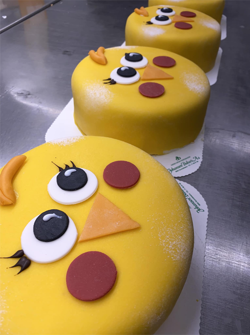 Fire gule kaker med ansikter av kyllinger, dekorert med fondant og fargerike detaljer.