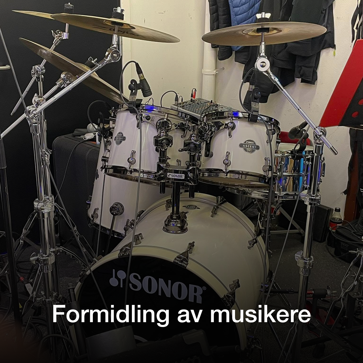 Et sett med trommer fra Sonor, inkludert skarptromme, cymbaler og trommestikker, i et øvingsrom.