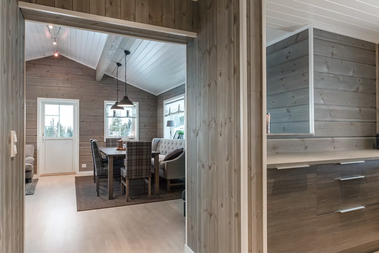 Moderne stue med trevegger, spisebord og komfortable møbler i en lys og innbydende atmosfære.