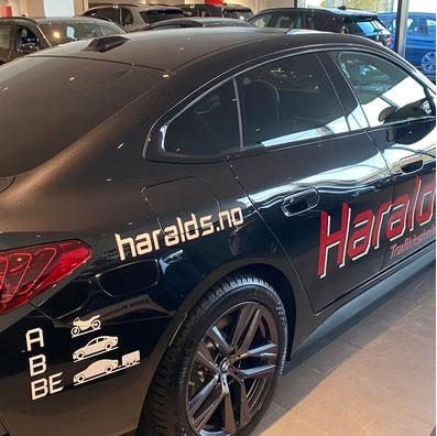 Svart bil med logoen "Haralds" og nettsiden "haralds.no" på siden.