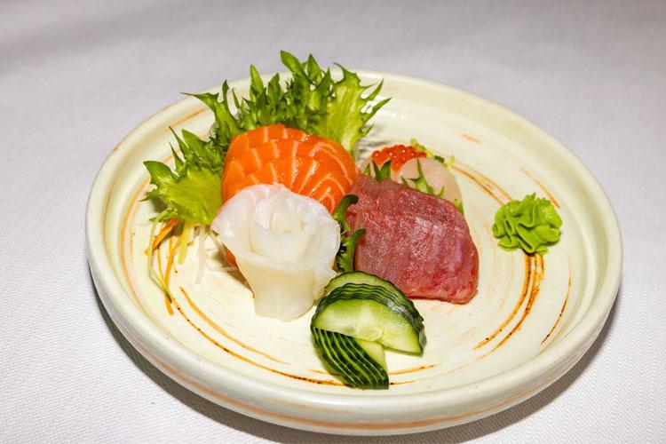 En tallerken med sushi som inneholder laks, tunfisk, reker, agurk og salat.