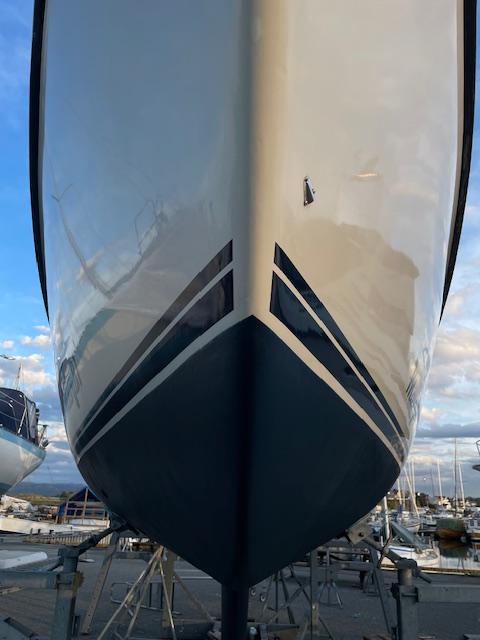 Båten sett fra fronten, med en glatt skrogdesign og reflekterende overflate i marinaen.