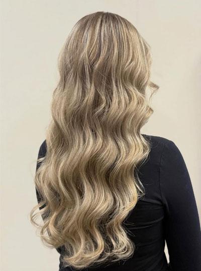 Langt, bølgete blondt hår sett bakfra, med en naturlig glans og myk tekstur.