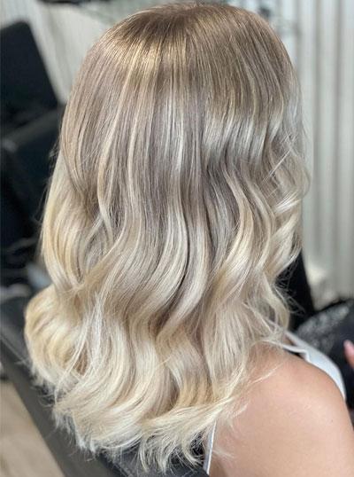 En kvinne med bølgete, blondt hår som glitrer i lyset, sett fra siden.