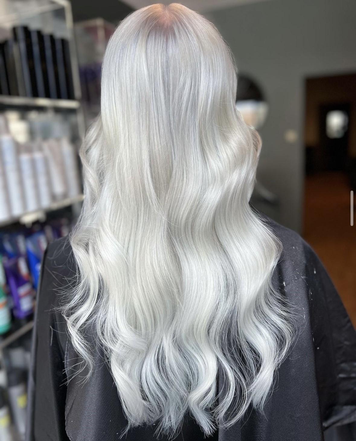 Langt, bølgete, platina blond hår sett bakfra i en frisørsalong.