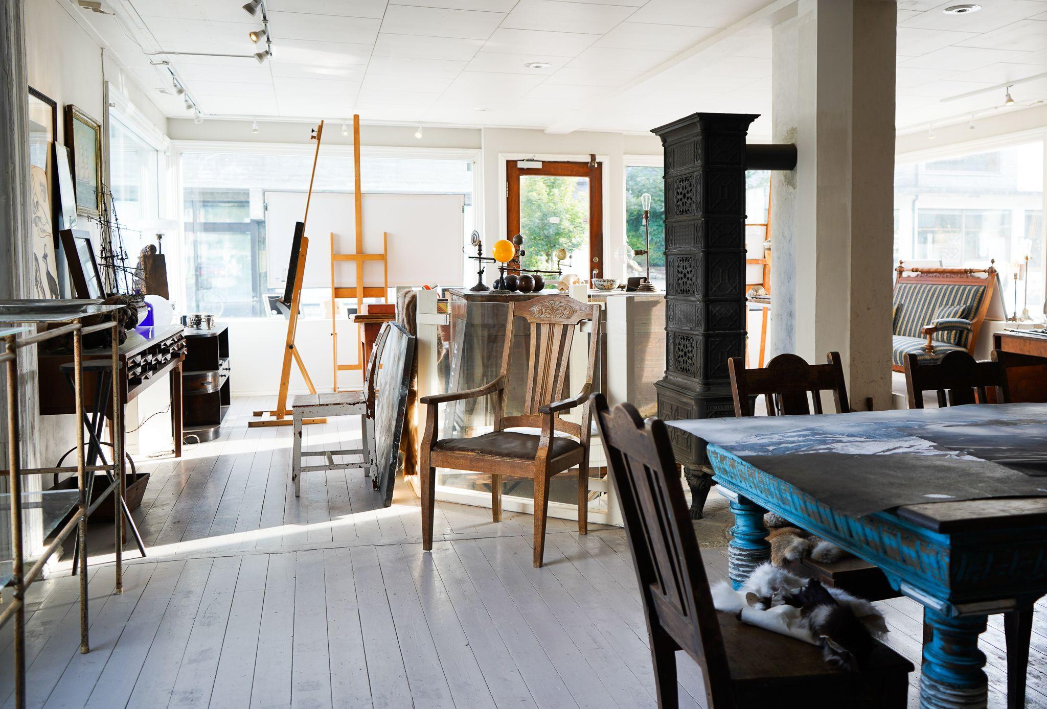 Lys og moderne interiør i en kunstnerisk leilighet med møbler, malerutstyr og en peis.